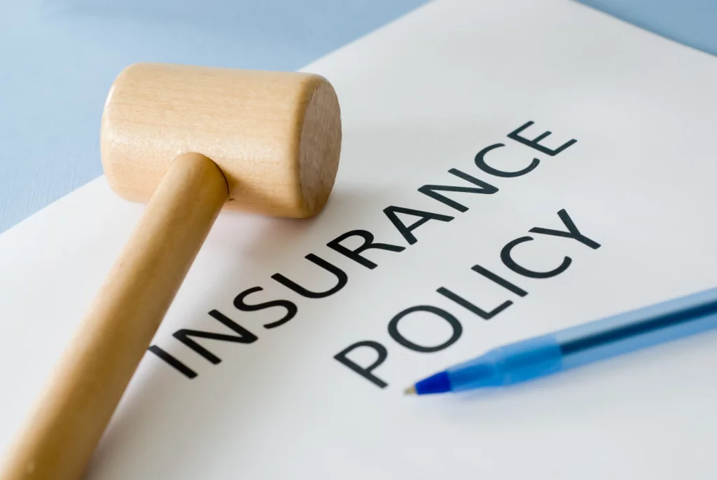 A wooden gavel and a blue pen rest atop a nonprofit insurance policy document.