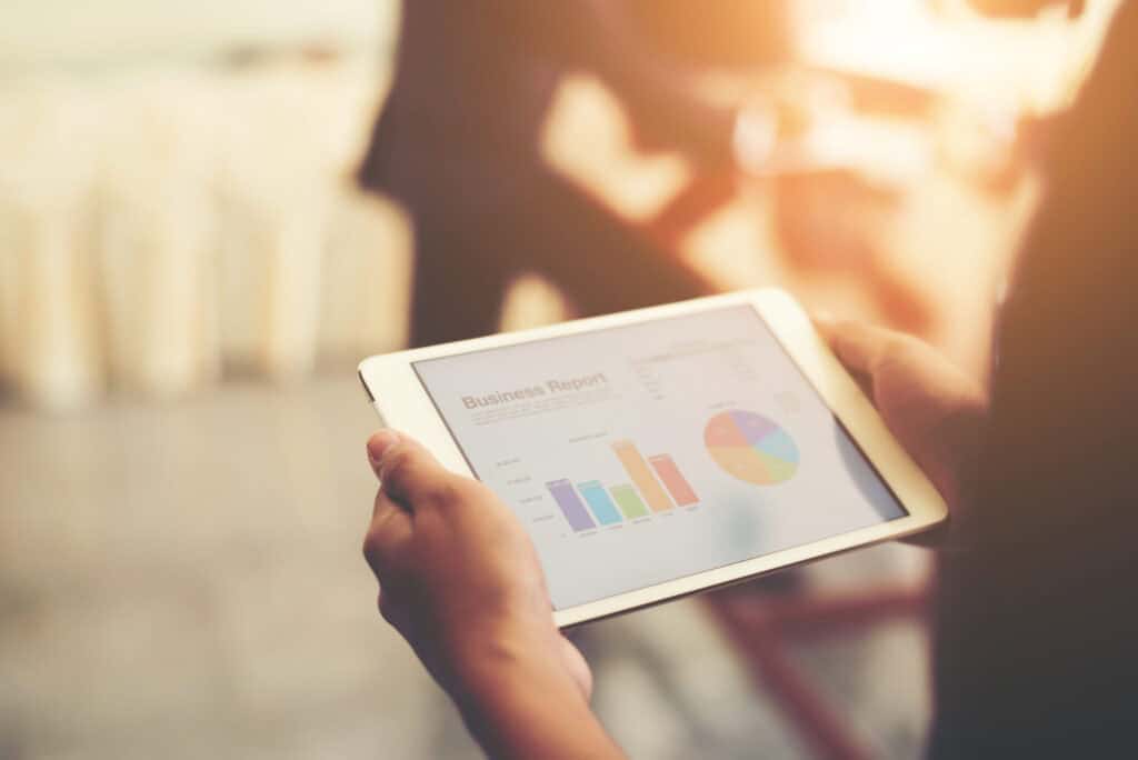 Person'd hand holding tablet with financial charts including unrelated business income tax