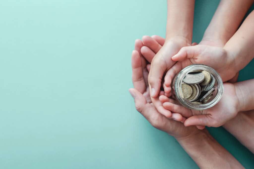Child and adult hands holding money Jar, shows Donations and Fundraising for Charity